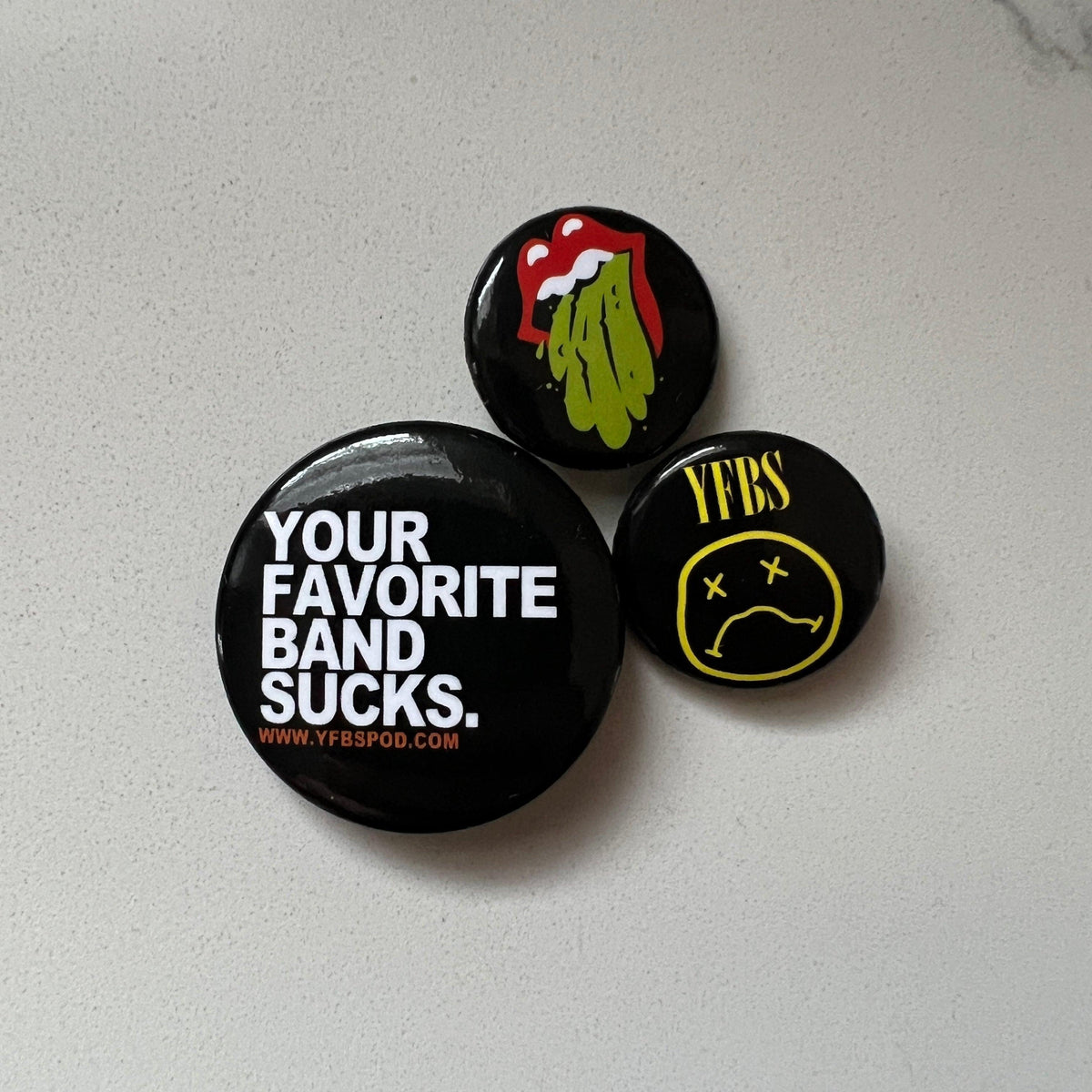 YFBS Pin Pack, three black enamel pins with Your Favorite Band Sucks logos on a white background